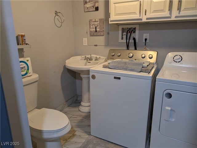 clothes washing area featuring marble finish floor, washing machine and dryer, and laundry area