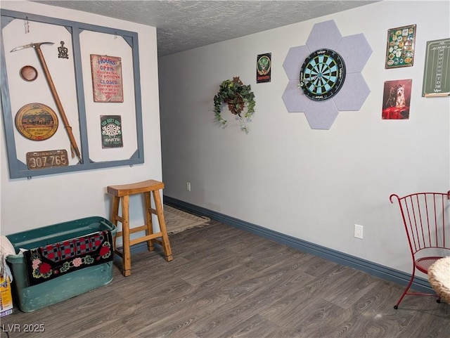 living area with wood finished floors, baseboards, and a textured ceiling