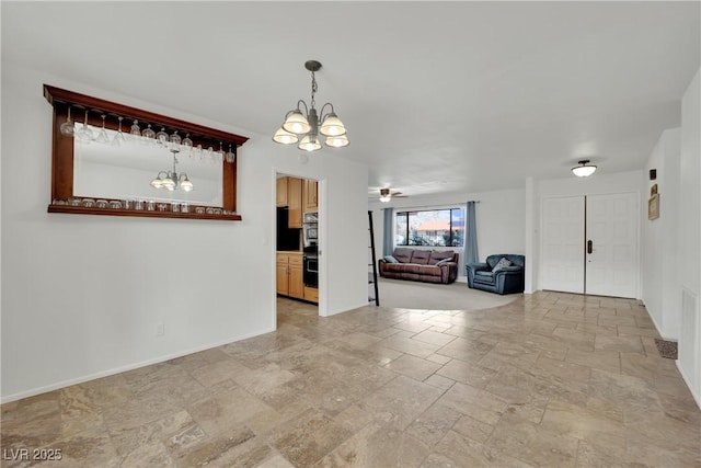 empty room featuring ceiling fan with notable chandelier, stone finish flooring, and baseboards