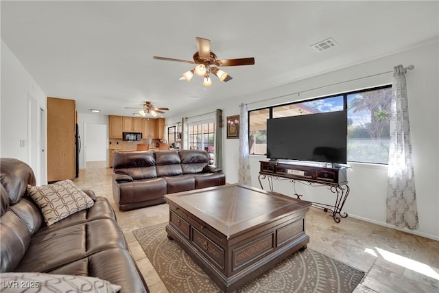 living room with baseboards, visible vents, and a ceiling fan