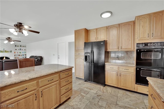 kitchen with decorative backsplash, light stone counters, stone finish flooring, light brown cabinetry, and black appliances