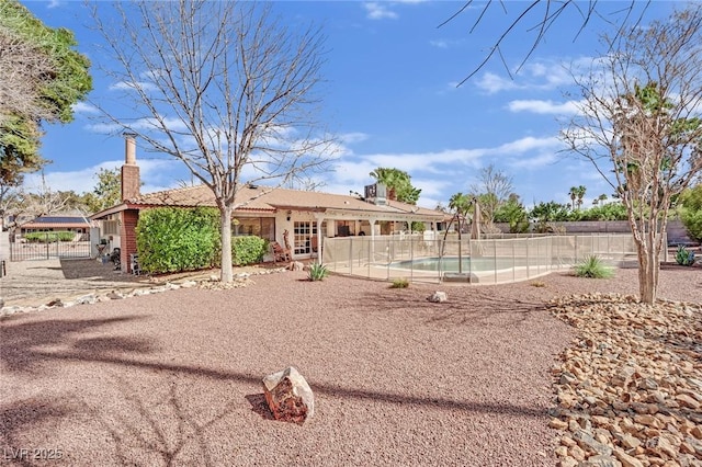 exterior space with a chimney, fence, and a fenced in pool