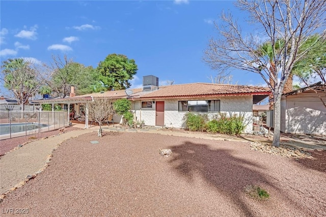 ranch-style home featuring a tiled roof, fence, cooling unit, and stucco siding