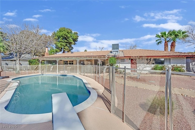 view of swimming pool featuring fence, a diving board, a fenced in pool, and a patio