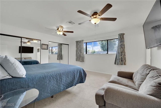 carpeted bedroom featuring multiple closets, visible vents, ceiling fan, and baseboards