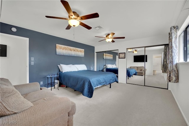 carpeted bedroom featuring multiple closets, visible vents, ceiling fan, and baseboards