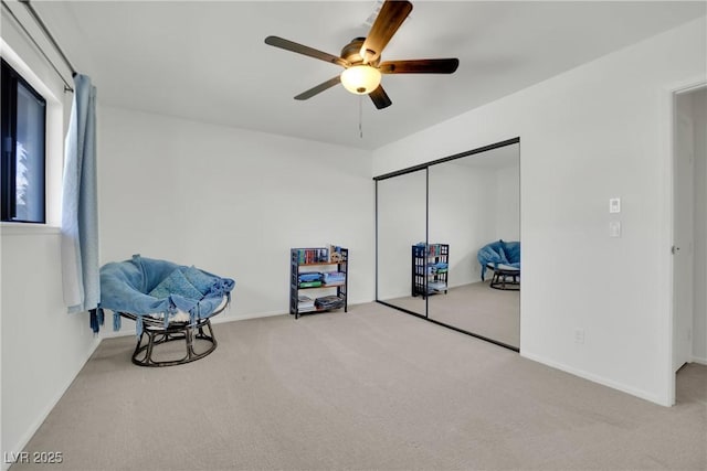 living area with ceiling fan, carpet, and baseboards