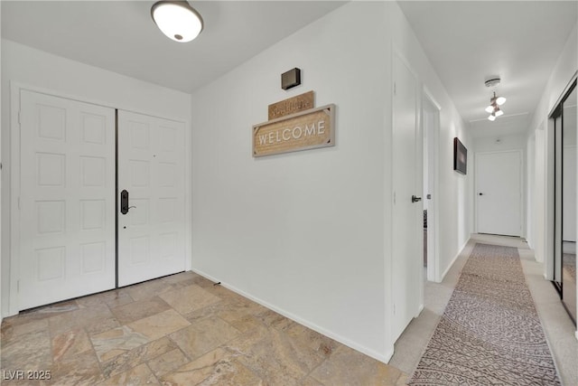 hall featuring baseboards and stone tile floors