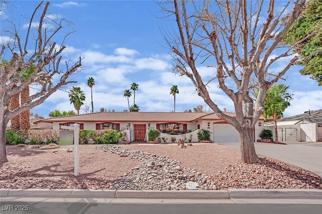 ranch-style home featuring an attached garage, a tile roof, fence, and concrete driveway