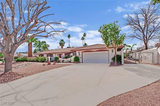 ranch-style house featuring a tile roof, stucco siding, a gate, a garage, and driveway