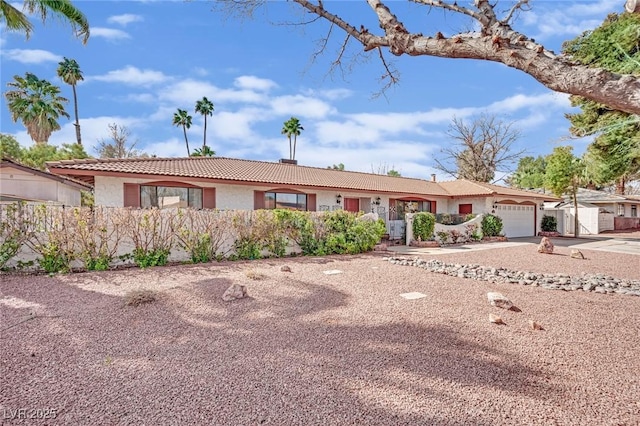 single story home featuring a garage, driveway, a tiled roof, fence, and stucco siding