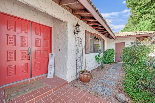 doorway to property featuring a tile roof and stucco siding