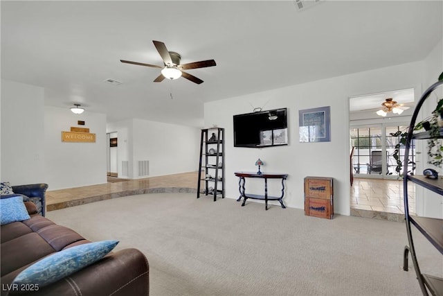 living room featuring carpet floors, visible vents, and a ceiling fan