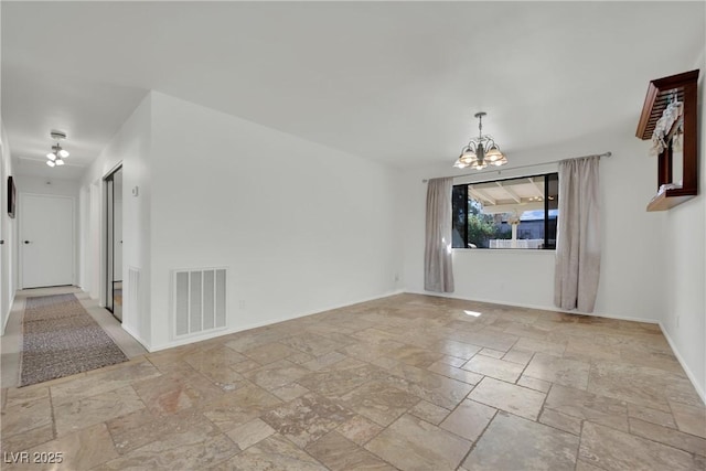 unfurnished room featuring stone tile flooring, baseboards, visible vents, and a notable chandelier