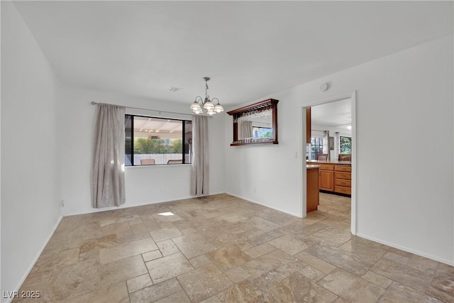 empty room featuring baseboards, a notable chandelier, visible vents, and stone tile floors