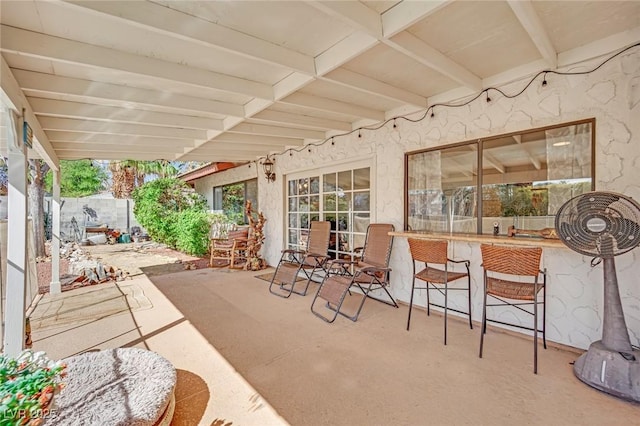 view of patio featuring outdoor dry bar and fence