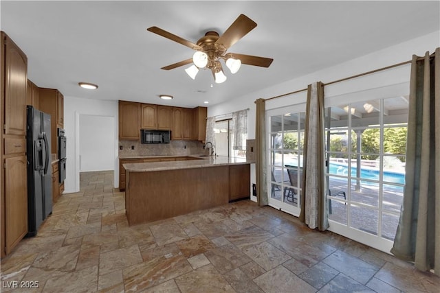 3681 S Rosecrest Cir, Las Vegas, NV 89121 - kitchen featuring black appliances, a peninsula, healthy amount of natural light, and stone tile floors