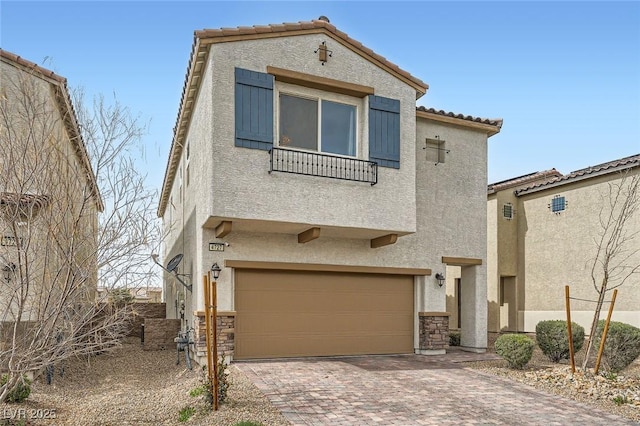 view of front of property featuring decorative driveway, stucco siding, an attached garage, stone siding, and a tiled roof