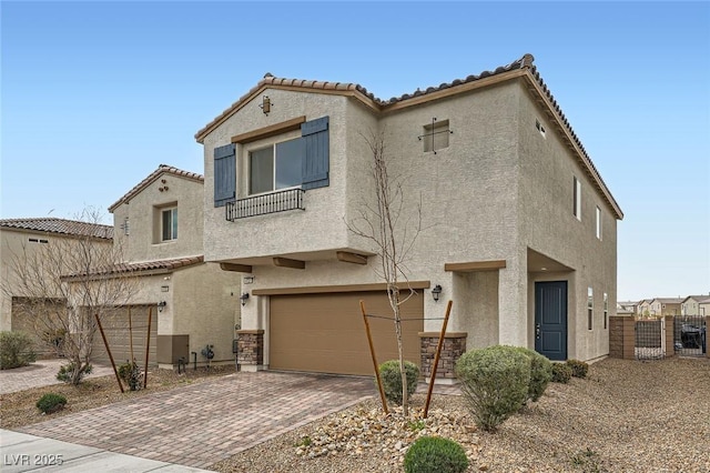 mediterranean / spanish home with a garage, a gate, decorative driveway, and stucco siding