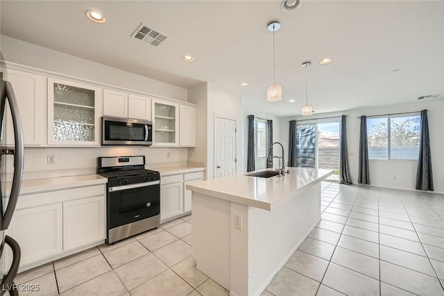 kitchen with light tile patterned floors, stainless steel appliances, a sink, visible vents, and light countertops