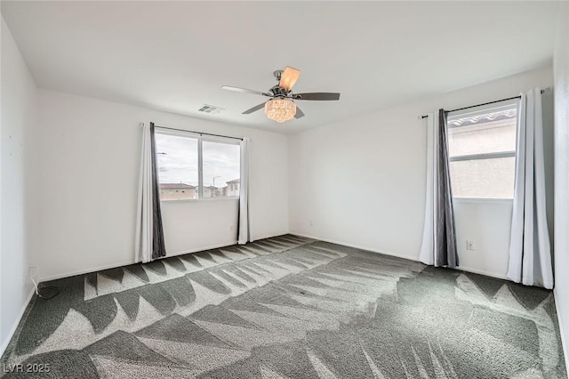 carpeted empty room featuring a healthy amount of sunlight, ceiling fan, and visible vents