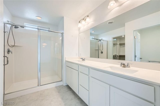 full bathroom featuring double vanity, tile patterned flooring, a shower stall, and a sink