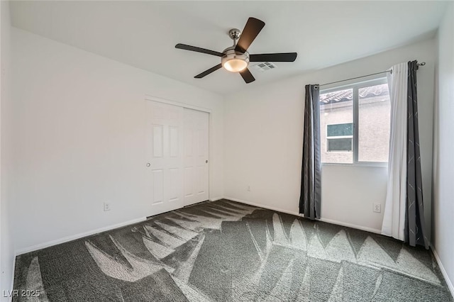 carpeted spare room with baseboards, visible vents, and a ceiling fan