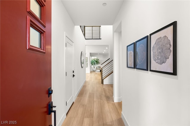 hallway featuring stairs, light wood finished floors, and baseboards