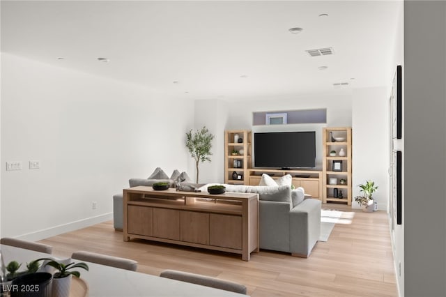 living area with visible vents, light wood-style flooring, and baseboards