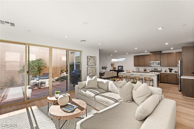 living area featuring light wood-type flooring, visible vents, and recessed lighting