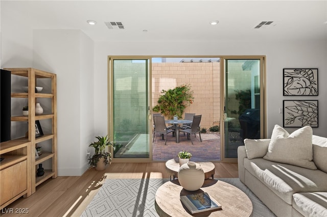 living area with light wood finished floors, visible vents, and recessed lighting