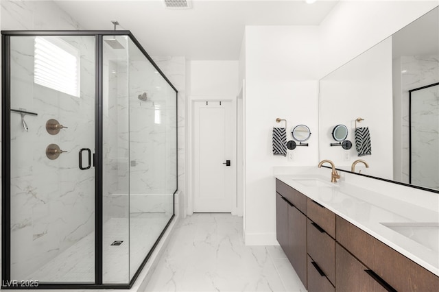 bathroom featuring a sink, baseboards, marble finish floor, a marble finish shower, and double vanity