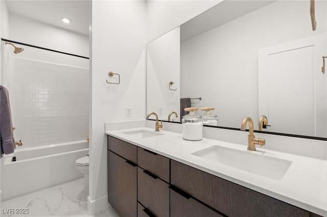 bathroom with marble finish floor, a sink, toilet, and double vanity