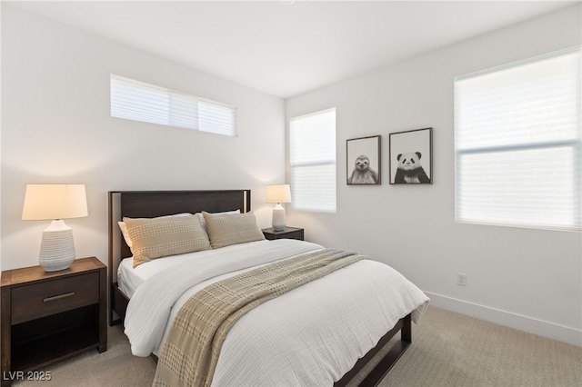 bedroom with light colored carpet, multiple windows, and baseboards