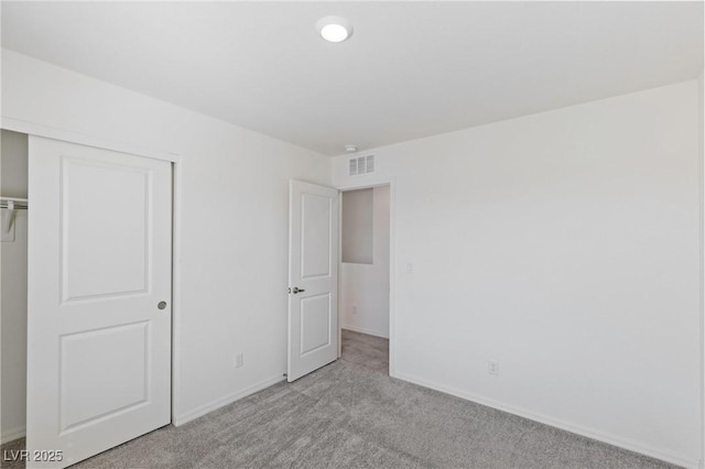 unfurnished bedroom featuring light carpet, a closet, visible vents, and baseboards