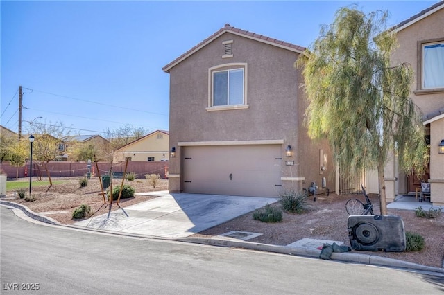 view of front of house featuring a tile roof, stucco siding, concrete driveway, an attached garage, and fence