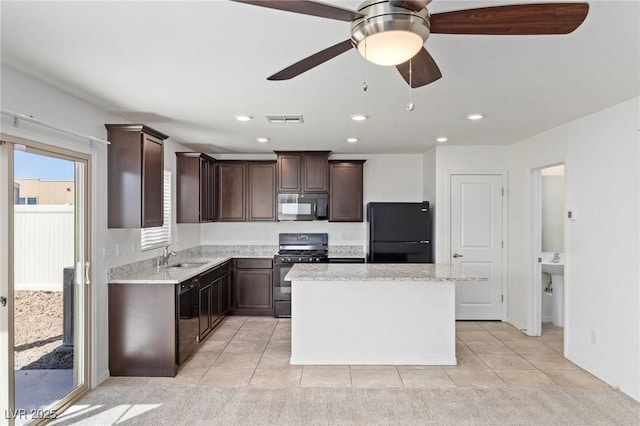 kitchen featuring dark brown cabinetry, visible vents, a kitchen island, and black appliances