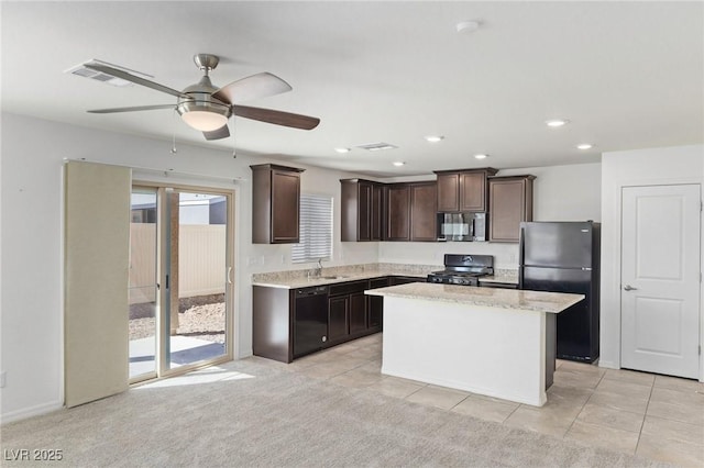 kitchen with light carpet, a kitchen island, a sink, dark brown cabinets, and black appliances