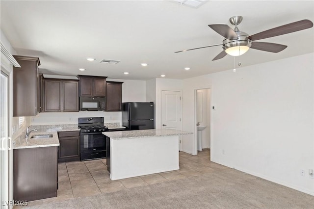 kitchen with dark brown cabinetry, a sink, visible vents, a center island, and black appliances