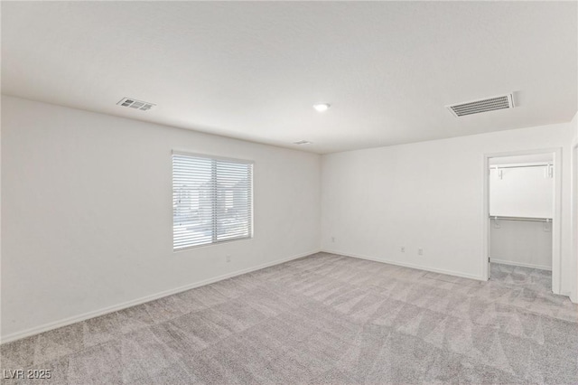 spare room featuring carpet flooring, visible vents, and baseboards