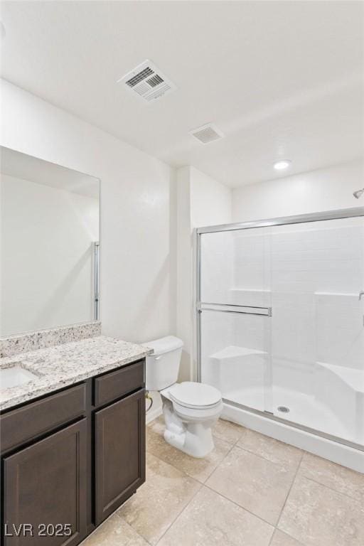 bathroom featuring toilet, vanity, visible vents, a shower stall, and tile patterned floors