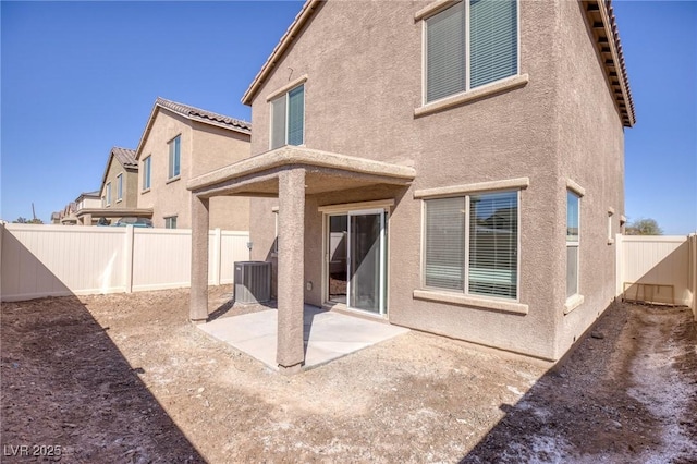 rear view of property featuring a patio area, a fenced backyard, central AC, and stucco siding