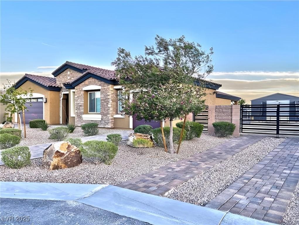 view of front of house with a gate, stone siding, a tiled roof, and stucco siding