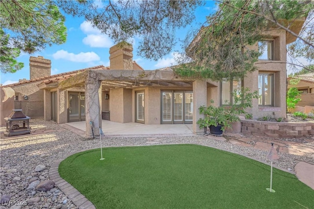 back of house featuring a patio area, a fire pit, and stucco siding