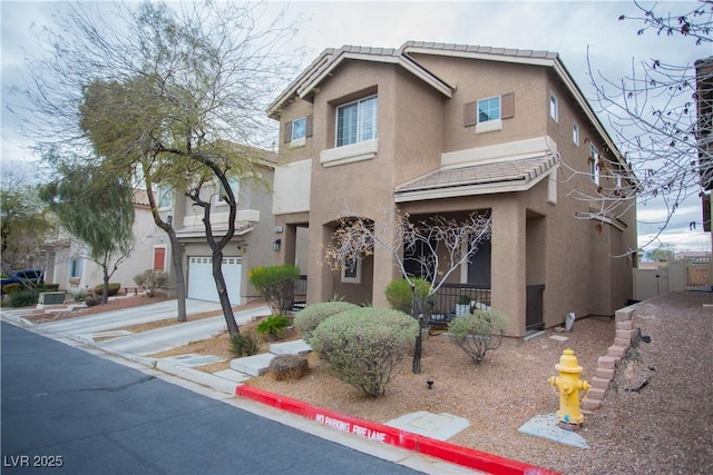 view of front of house featuring stucco siding, a tiled roof, and driveway