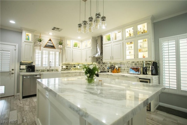 kitchen with visible vents, dishwasher, wall chimney range hood, and decorative backsplash