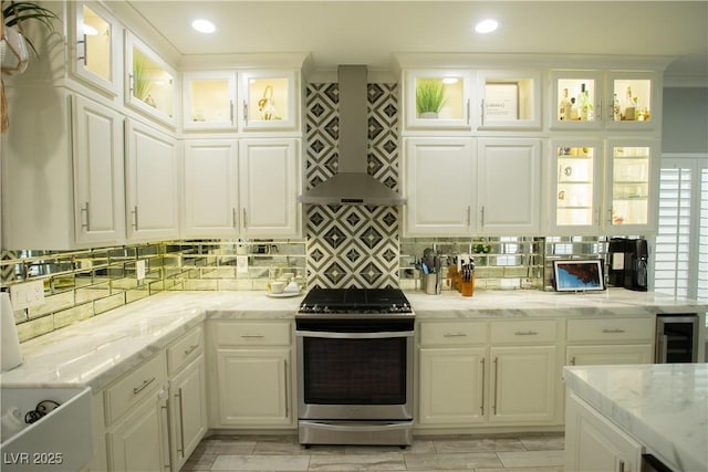 kitchen with white cabinets, wall chimney exhaust hood, gas stove, and backsplash