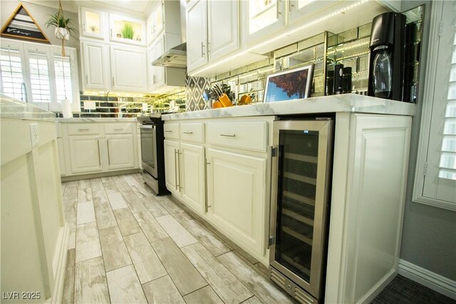 bar with stainless steel range with electric stovetop, beverage cooler, wall chimney range hood, decorative backsplash, and wood tiled floor