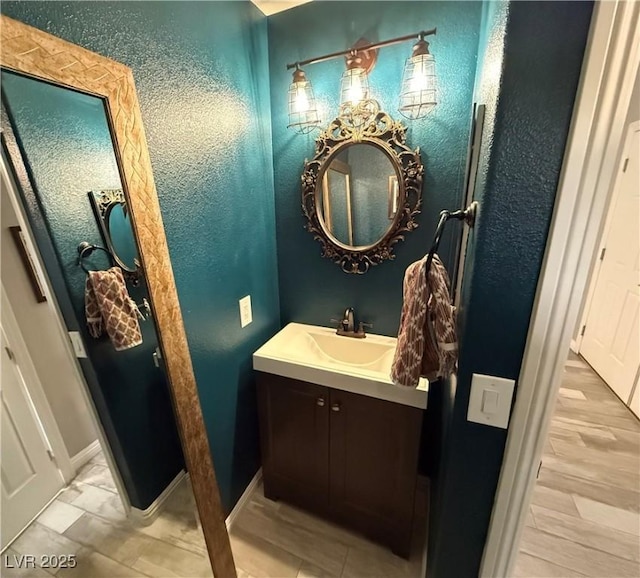 bathroom with vanity, baseboards, and a textured wall