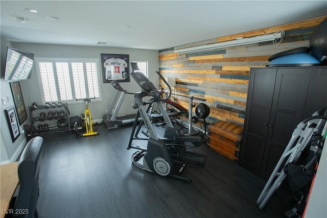 workout room with visible vents, wooden walls, and wood finished floors